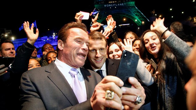 Arnold Schwarzenegger, dans une foule, prenant un égoportrait avec le président français Emmanuel Macron. Arnold Schwarzenegger, dans une foule, prenant un égoportrait avec le président français Emmanuel Macron.