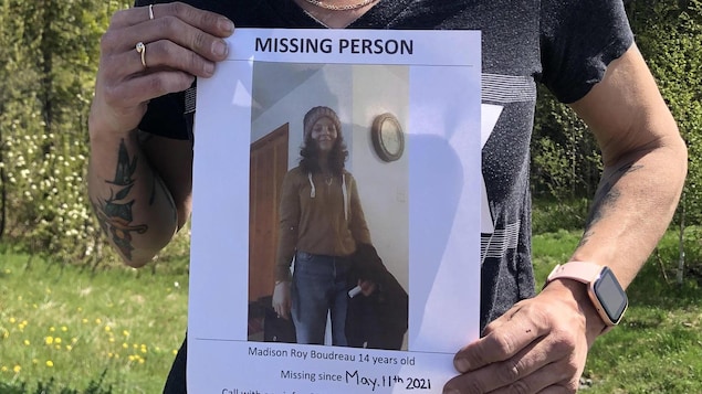 Une personne exhibe une affiche de personne disparue.