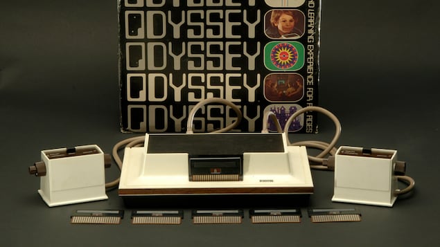 Une boîte et une console de jeu vidéo, avec deux manettes et cinq cartouches. 