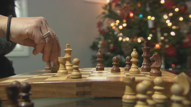 Une personne joue aux échecs dans son salon.