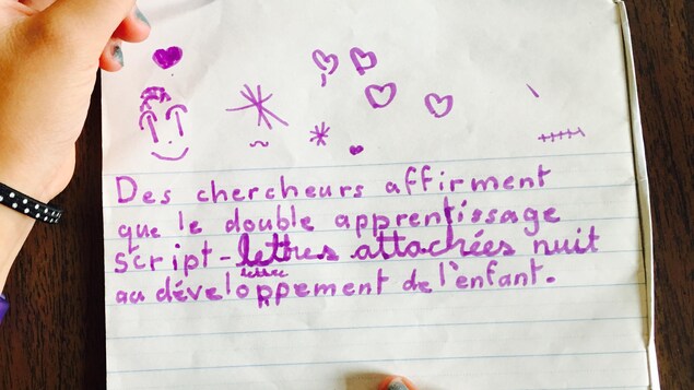 Une écolière écrit à la main en lettres détachées et attachées dans un cahier. Une écolière écrit à la main en lettres détachées et attachées dans un cahier.