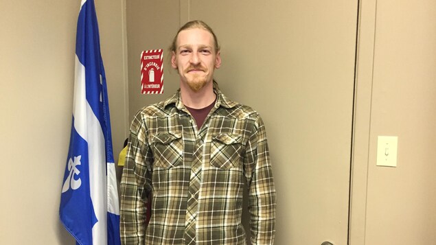 Un homme prend la pose à côté d'un drapeau du Québec. Un homme prend la pose à côté d'un drapeau du Québec.