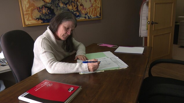 Nathalie Ross signe un document à son bureau.