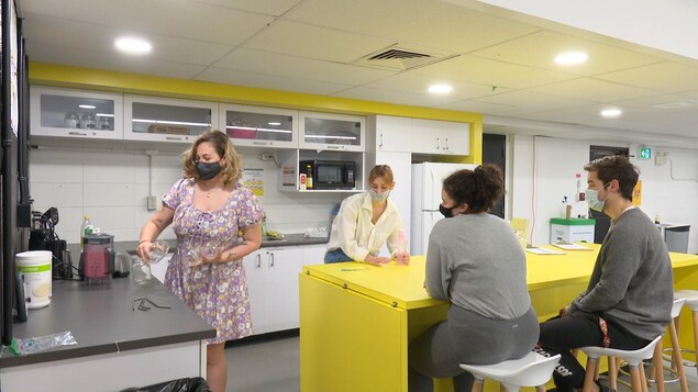 Trois jeunes accoudés à un ilot de cuisine à la maison des jeunes.