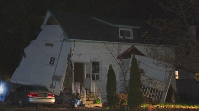 Photo d'une maison blanche dont l'un des murs est détaché de sa structure. Photo d'une maison blanche dont l'un des murs est détaché de sa structure.