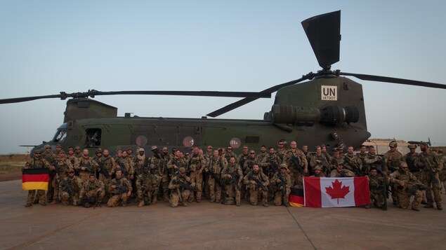 Des soldats avec des drapeaux allemands et canadiens devant un Chinook. Des soldats avec des drapeaux allemands et canadiens devant un Chinook.