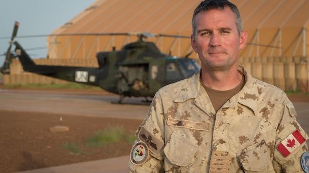 Le Colonel Christopher McKenna en avant-plan. un hélicoptère de combat Griffon en arrière-plan. Le Colonel Christopher McKenna en avant-plan. un hélicoptère de combat Griffon en arrière-plan.