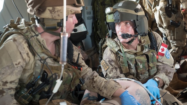 Dans un hélicoptère, un entraînement de service médical d'urgence par deux militaires canadiens.