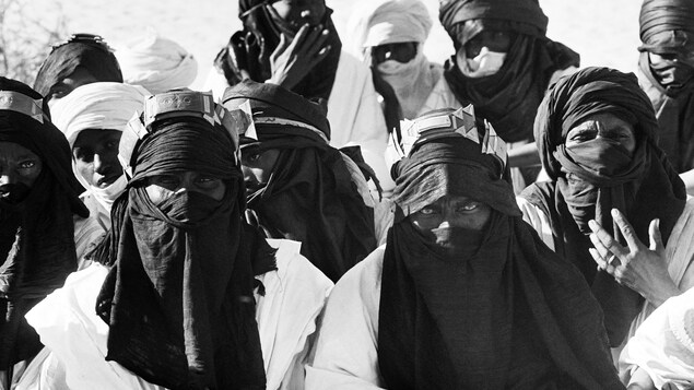 Une photographie d'archive en noir et blanc illustrant des hommes touaregs portant leurs chèches, foulards traditionnels. Une photographie d'archive en noir et blanc illustrant des hommes touaregs portant leurs chèches, foulards traditionnels.