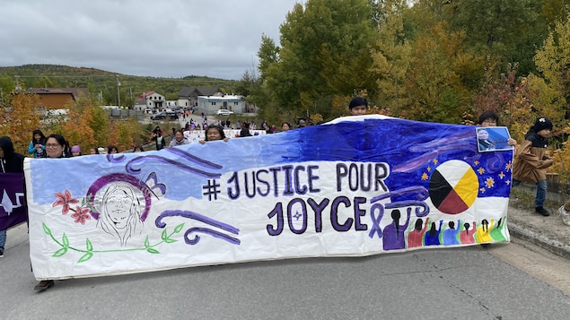 Des gens tiennent une bannière où est écrit « Justice pour Joyce ».