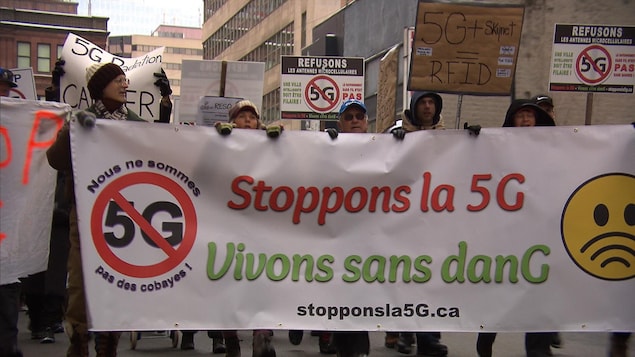 Une bannière sur laquelle est inscrit: Stoppons la 5G est tenue par plusieurs manifestants.