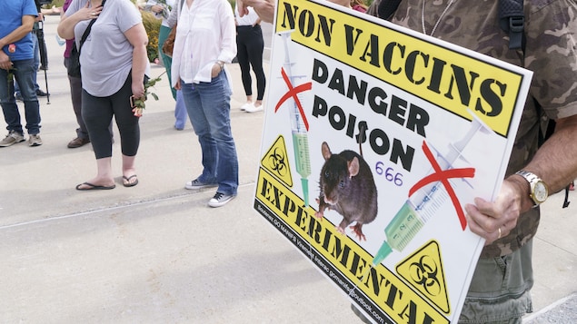 Gros plan sur une pancarte que brandit un manifestant lors d'un rassemblement antivaccins devant un hôpital montréalais. On peut lire Non Vaccins, Danger poison, 666, Expérimental.