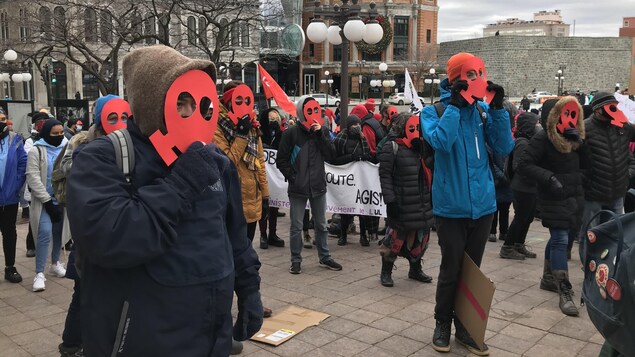 Des personnes portent un masque rouge en carton pour dénoncer le plan vert.