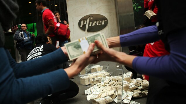 Des manifestants empilent des centaines de faux billets de banque devant l'entrée de Pfizer. Des manifestants empilent des centaines de faux billets de banque devant l'entrée de Pfizer.