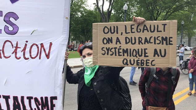 Une femme tient une pancarte où on peut lire : « Oui, Legault, on a du racisme systémique au Québec », lors d'une manifestation devant l'Assemblée nationale.