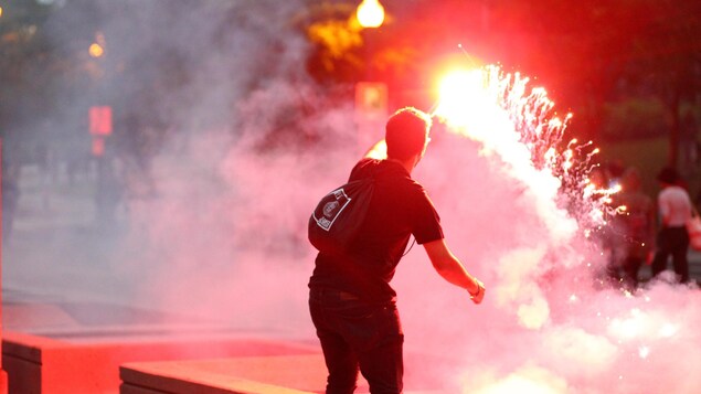 Vue de dos d’un manifestant qui agite un feu de détresse. Vue de dos d’un manifestant qui agite un feu de détresse.