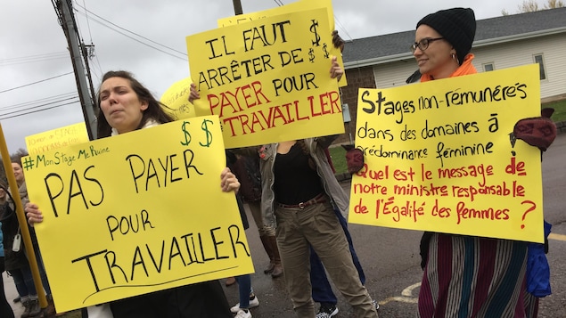 Des manifestantes étudiantes, pancartes à la main, dénoncent les stages non rémunérés dans le milieu universitaire.