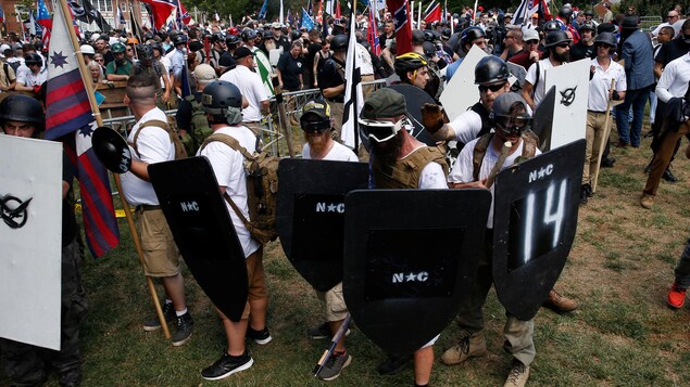 Des hommes vêtus de T-shirts blancs et portant des casques tiennent des boucliers noirs. Des hommes vêtus de T-shirts blancs et portant des casques tiennent des boucliers noirs.