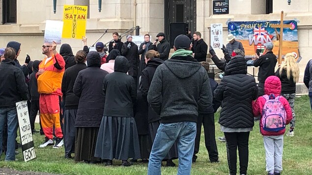 Des gens de dos avec des pancartes.