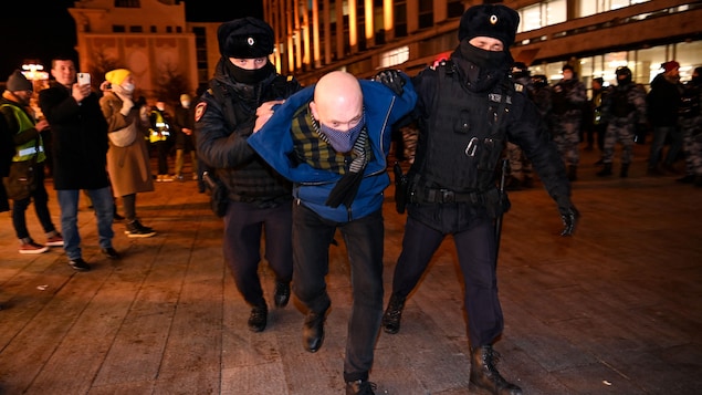 Deux policiers tiennent arrêtent un homme.