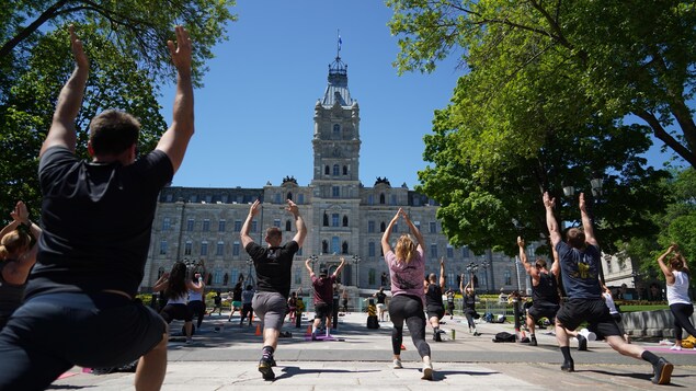 Des yogis tendent les mains vers le ciel en faisant une fente devant le Parlement. 