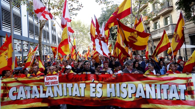 Des gens marchent derrière une bannière lors d’une manifestation en faveur du maintien de l’union entre la Catalogne et l’Espagne, à Barcelone, le 8 octobre 2017. Des gens marchent derrière une bannière lors d’une manifestation en faveur du maintien de l’union entre la Catalogne et l’Espagne, à Barcelone, le 8 octobre 2017.