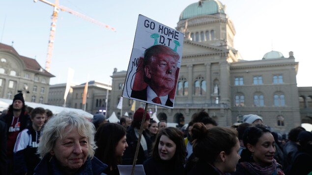 Une femme, parmi une foule, tient une affiche contre la venue de Donald Trump. Une femme, parmi une foule, tient une affiche contre la venue de Donald Trump.