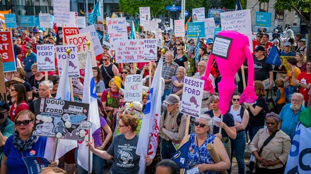 Des personnes tenant diverses pancartes lors d'une manifestation.