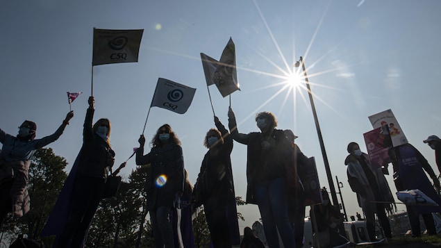 Des manifestants avec des pancartes à contre-jour.