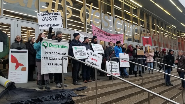 Des manifestants environnementalistes devant le Palais des congrès de Montréal tiennent des affiches.
