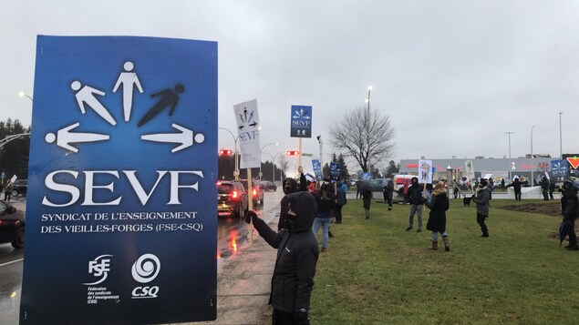 Des manifestants le long d'un boulevard sous la pluie.