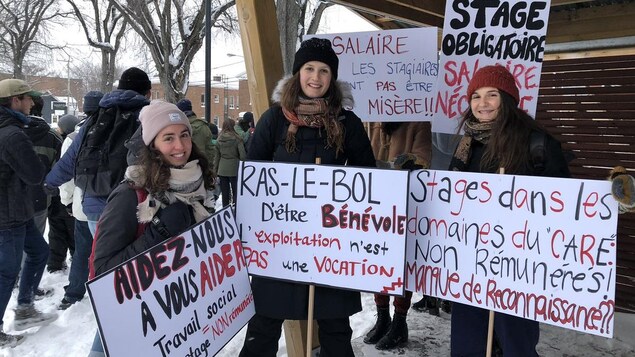 Trois étudiantes font la pose avec des pancartes qui dénoncent la non rémunération des stages.