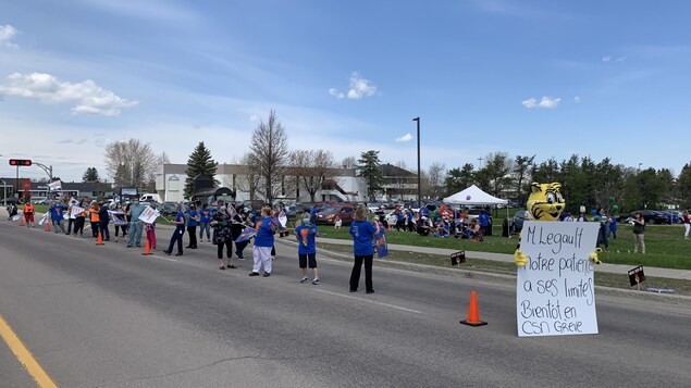 Des employés du réseau de la santé manifestent en bordure d'une rue.