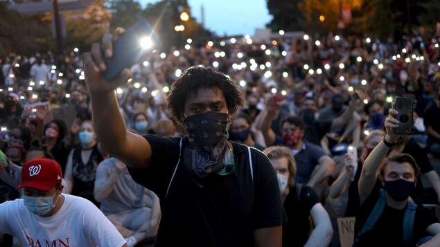 Des manifestants brandissent leur téléphone intelligent lors d'une marche.