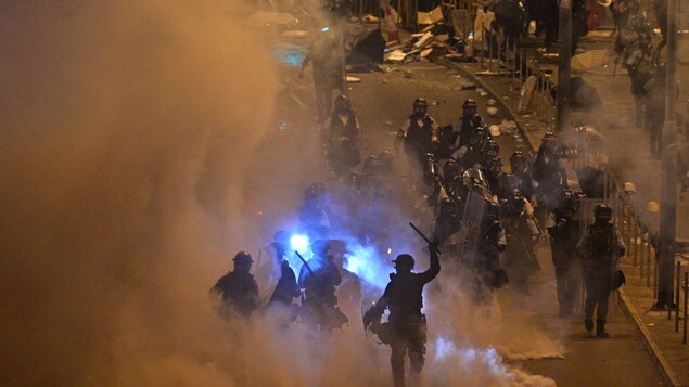 Des policiers utilisant des matraques et des tirs de gaz lacrymogène pour disperser une foule de manifestants.