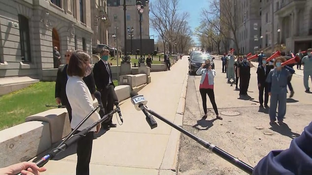 La ministre de la Santé Danielle McCann, masquée, s'adresse aux manifestants.
