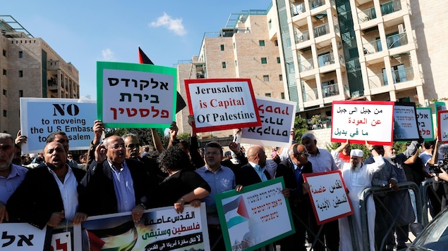 Plusieurs personnes brandissent des pancartes, rédigées en anglais et en arabe. « Jérusalem est la capitale de la Palestine» , peut-on lire sur l'une d'elles.