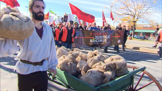 Un homme déguisé en Robin des bois se promène avec des sacs d'argent à côté des manifestants.