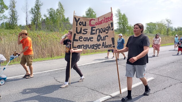 Des jeunes marchent sur une route en brandissant une pancarte.