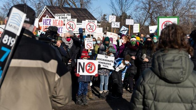 Des manifestants brandissent des affiches d'opposition à la loi 21 à Chelsea, au Québec, en décembre 2021.