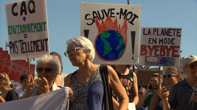 Des manifestants tiennent des pancartes où on lit des slogans pour l'environnement