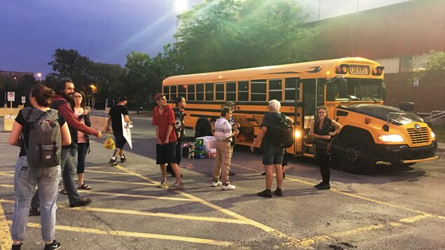 Des manifestants sont réunis devant un autobus scolaire qui les transportera jusqu'à Québec.