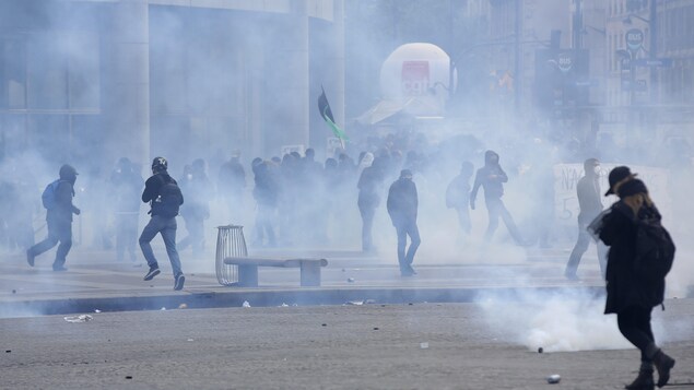 Des jeunes circulent à travers les gaz lacrymogènes à Paris dans le cadre des manifestations du 1er Mai.