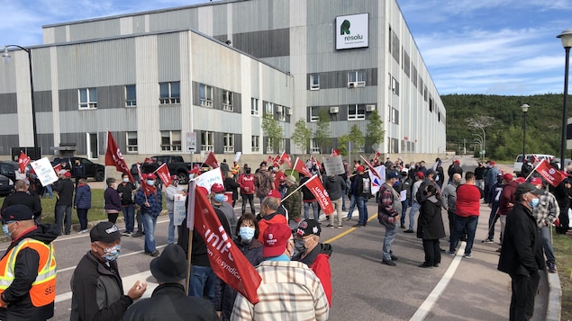 Plusieurs dizaines de manifestants devant l'usine avec des drapeaux rouges du syndicat Unifor à la main.