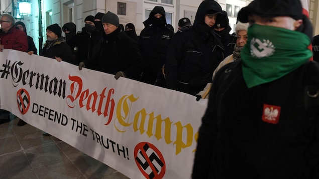 Des manifestants masqués tiennent une bannière sur laquelle on peut lire « Defend the truth » (Défendre la vérité). Des manifestants masqués tiennent une bannière sur laquelle on peut lire « Defend the truth » (Défendre la vérité).