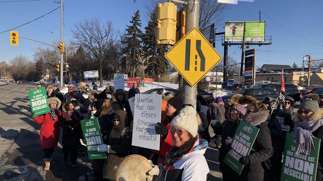 Des manifestants avec des pancartes au coin d'une rue.