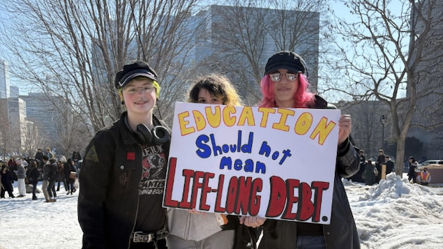 Trois étudiants tenant une affiche disant « Éducation ne devrait pas dire une date à vie » lors de la manifestation du 4 mars 2026 à Queen’s Park (Toronto).