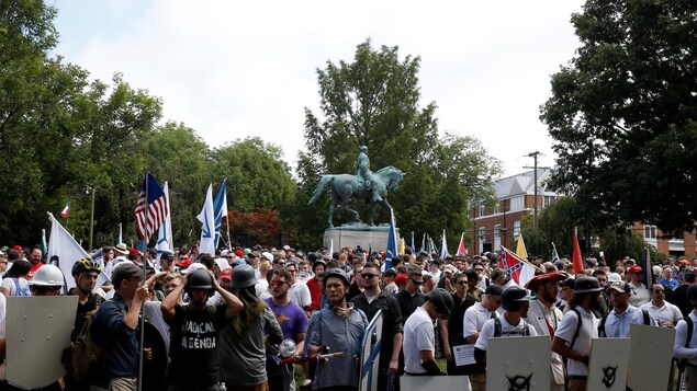 Des suprémacistes blancs sont réunis au pied de la statue du général Robert E. Lee, arborant des drapeaux et des boucliers