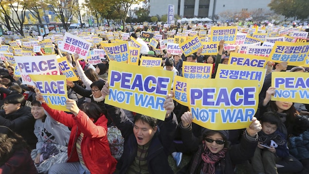 Les manifestants brandissent des affiches sur lesquelles on peut lire "Peace, not war" ("Paix, pas de guerre"). Les manifestants brandissent des affiches sur lesquelles on peut lire "Peace, not war" ("Paix, pas de guerre").