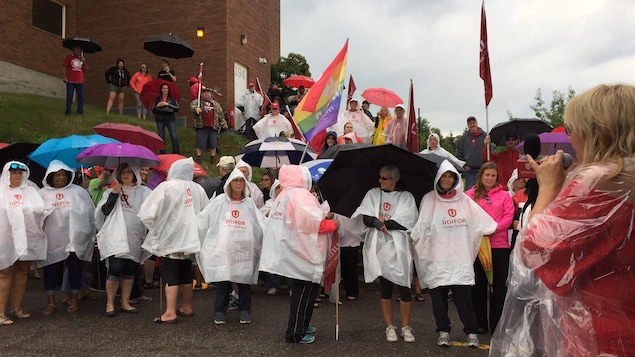 Une groupe de personnes portant des imperméables et des parapluies pendant un rassemblement. Une groupe de personnes portant des imperméables et des parapluies pendant un rassemblement.